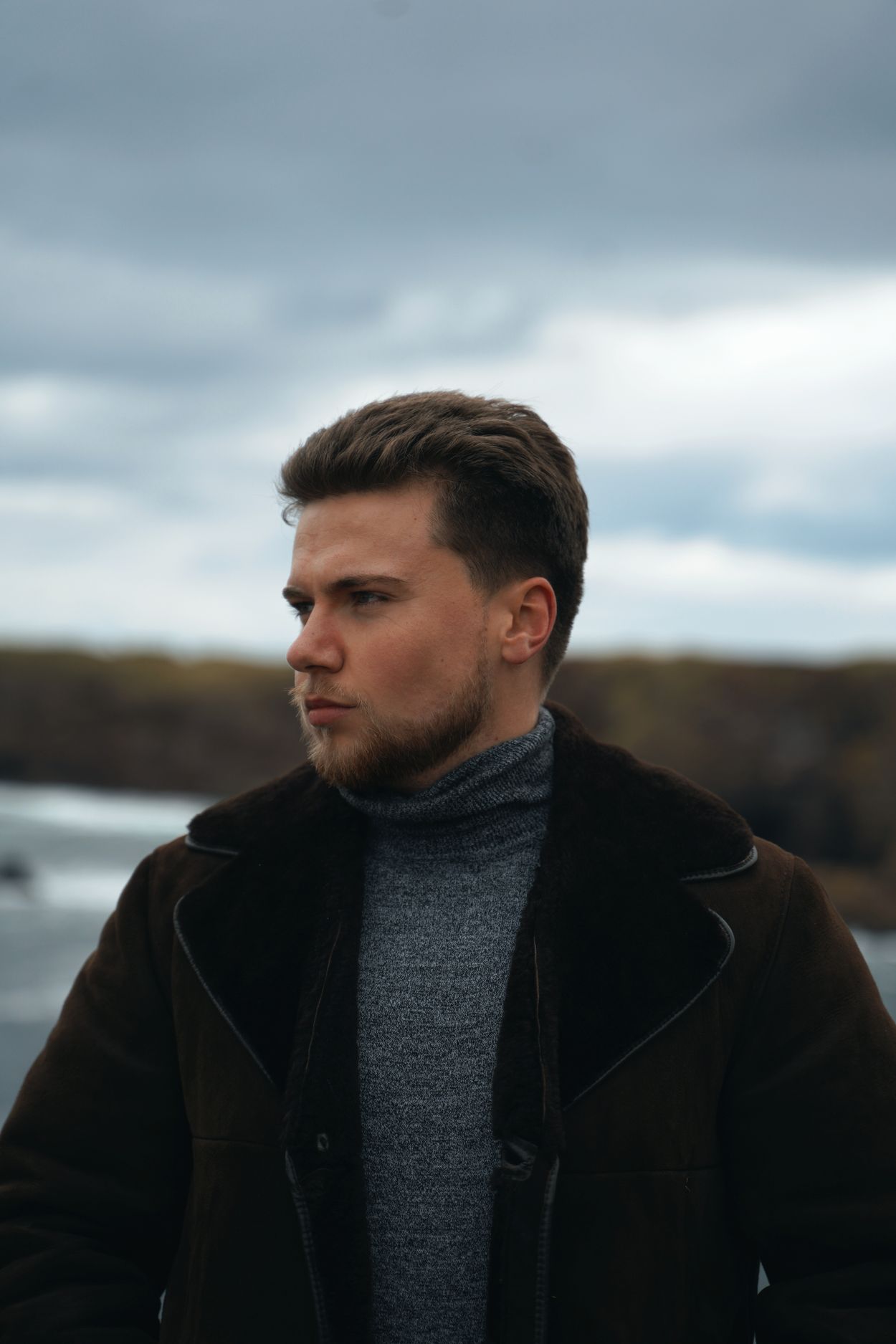 Man in a grey turtleneck under a brown winter jacket
