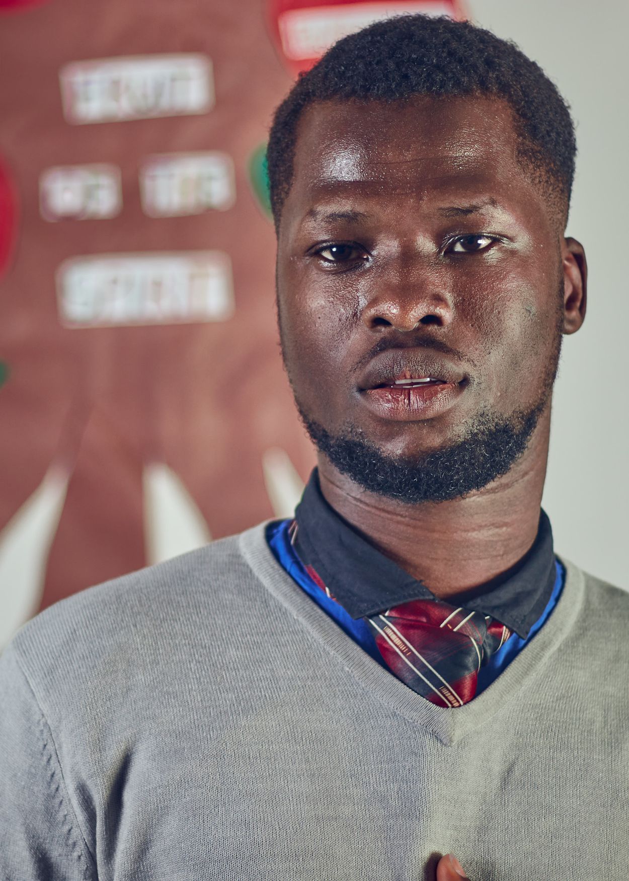 Man wearing a grey V-neck sweater with a shirt and tie