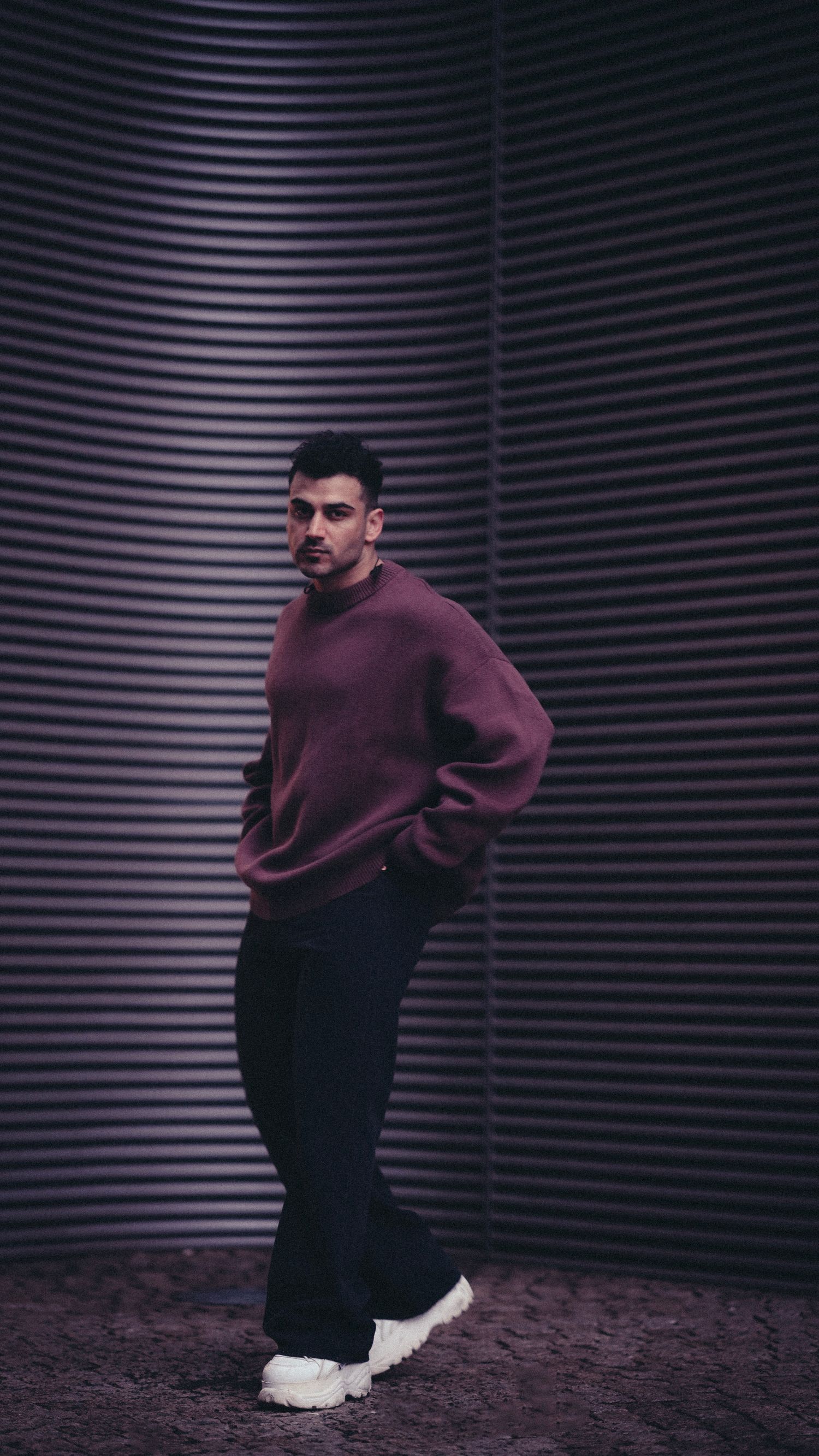 Man wearing relaxed streetwear with wide jeans, a loose sweater and sneakers