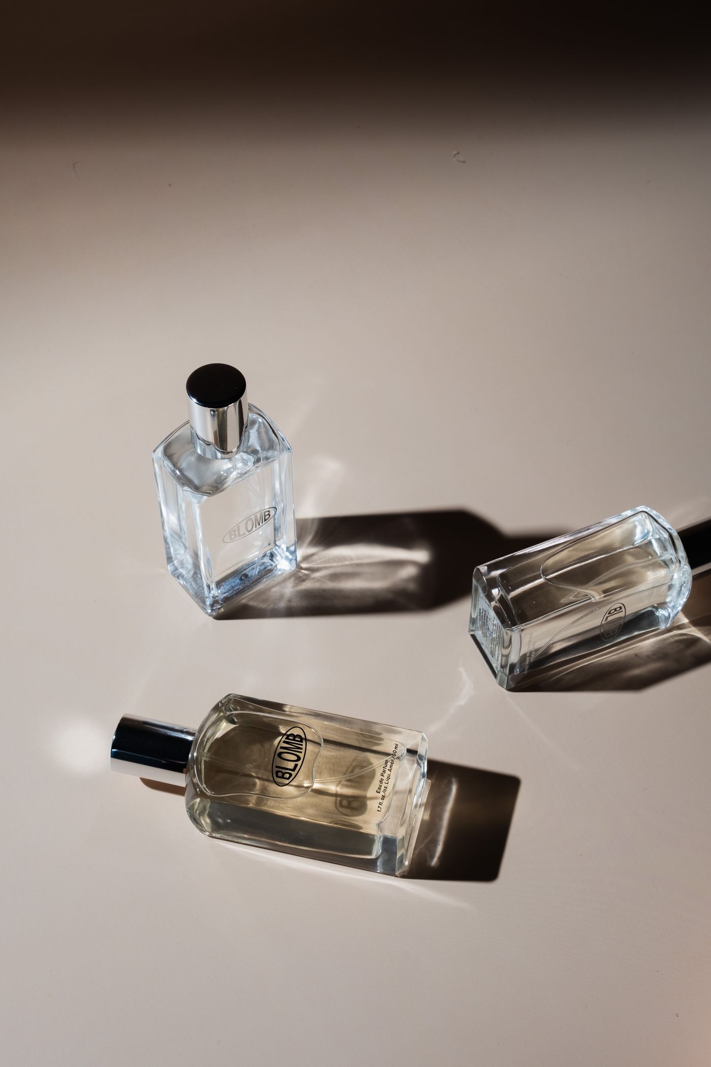Three elegant perfume bottles arranged on a minimalist surface in natural light