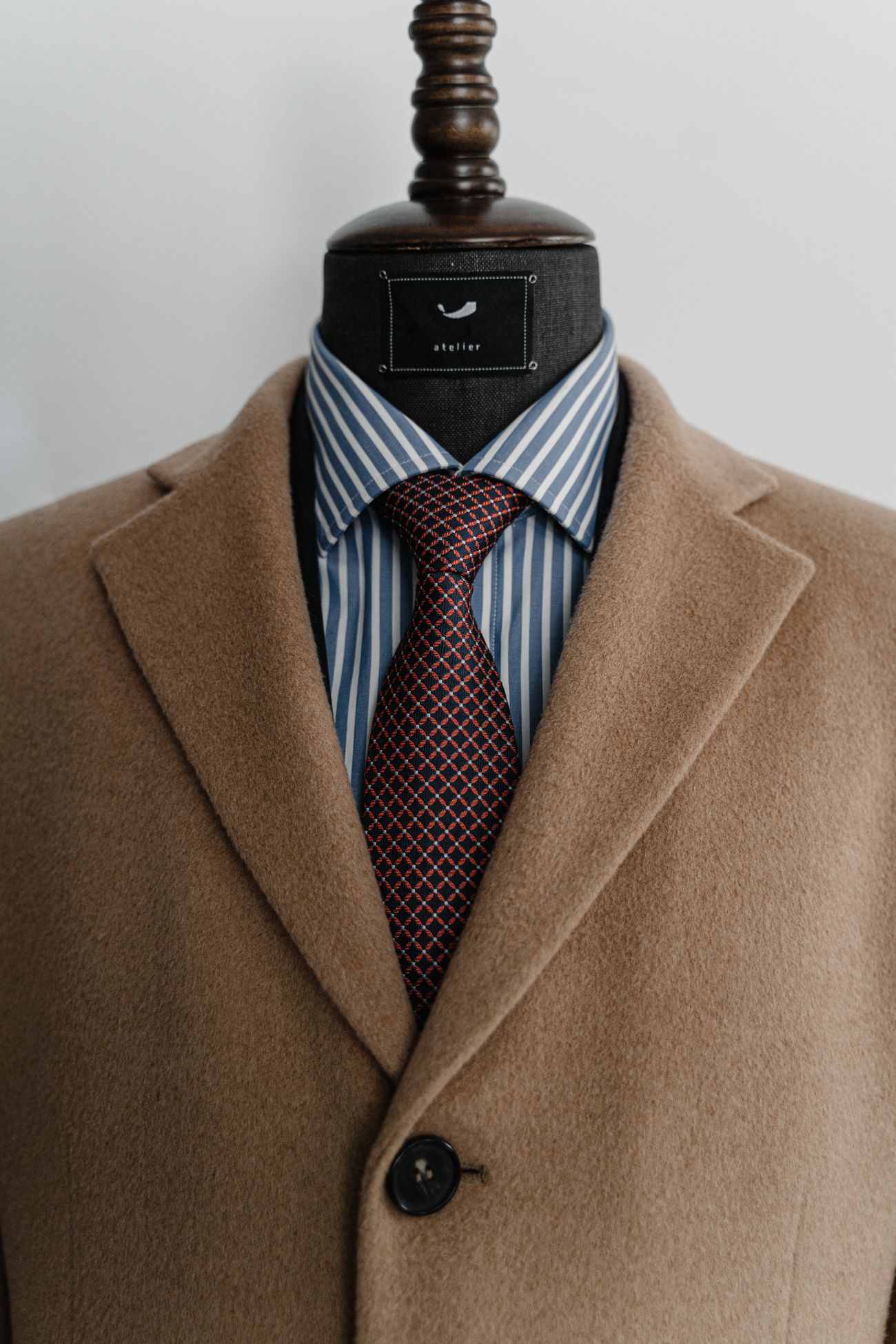 Close-up of a brown tailored jacket with a striped shirt and tie