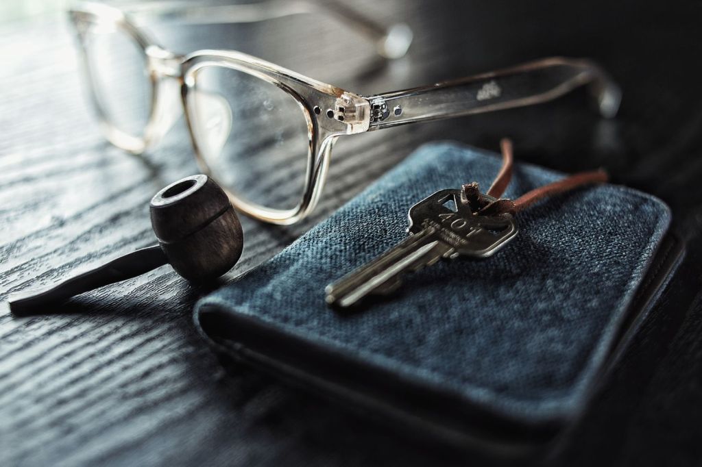 Antique tobacco pipe beside eyeglasses and a key on a wooden table